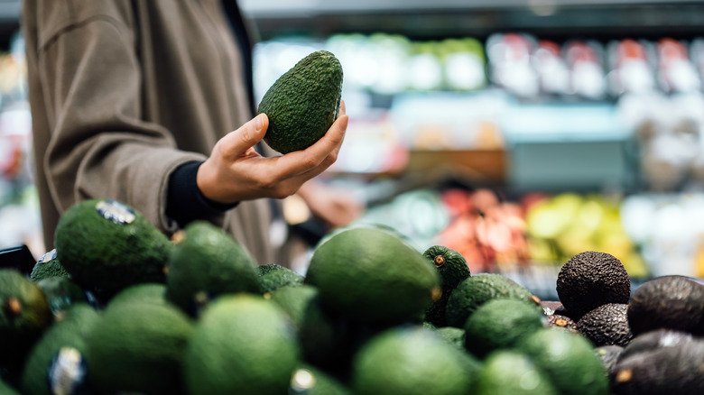 Shopper inspects an avocado at a grocery store