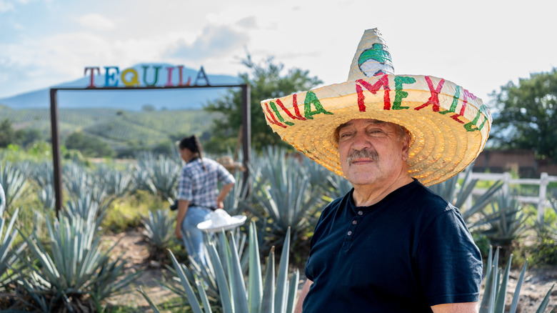 Tequila farmer stands in front of agave plants