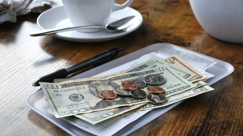 A restaurant check with cash tip and coins