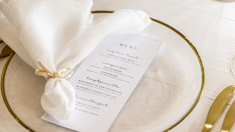 A formal place setting with napkin and curated menu