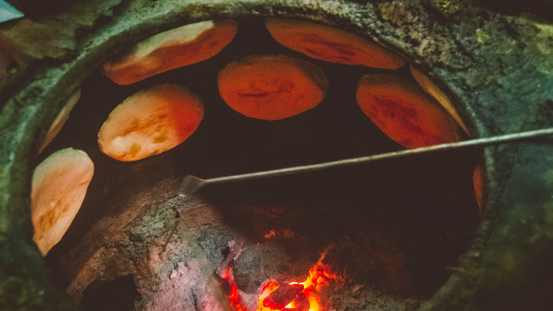 a tandoor oven with flatbread stuck on the inside