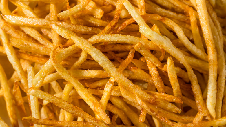 A close-up of a pile of golden fried shoestring French fries