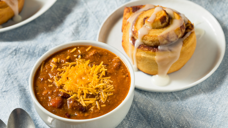 Bowl of chili and a cinnamon roll on a table