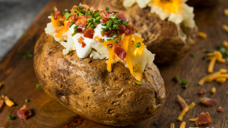 Closeup of baked potato with cheese, bacon, chives, and sour cream