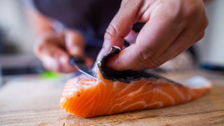 Someone separating the skin from salmon with a knife