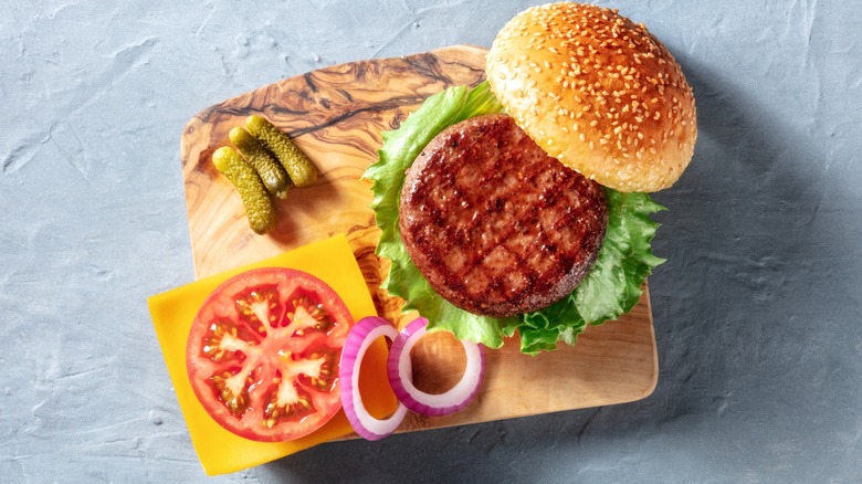 Wooden tray with burger on bun and toppings