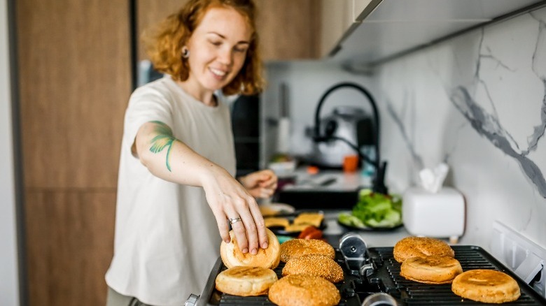 Women toasting hamburger buns on grill in kitchen