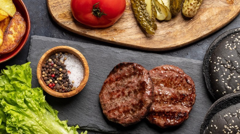 Grilled hamburgers on slate board with toppings