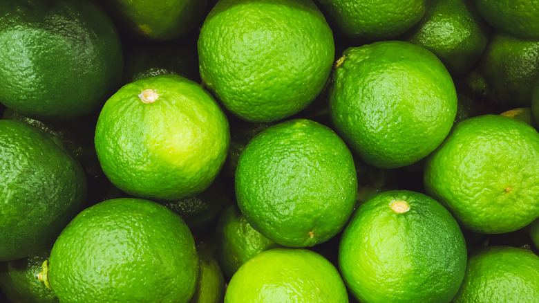 A pile of green limes in a bin