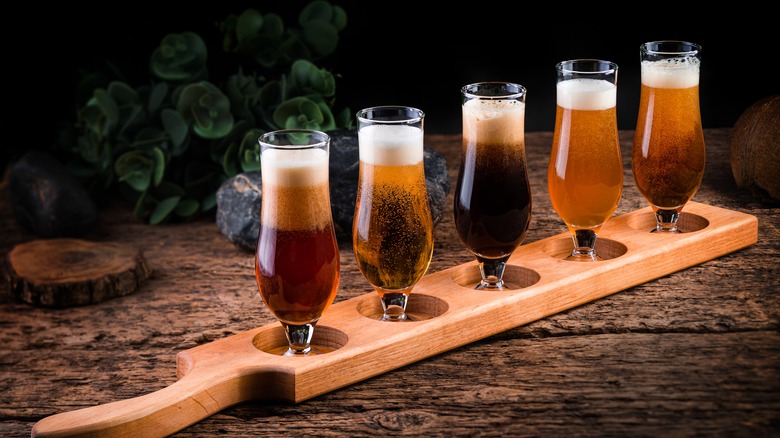 a beer flight in tulip glasses sitting in a wooden flight board