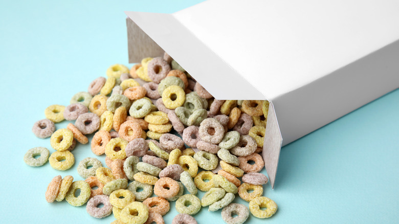 white cereal box with round colored cereal spilling out on light blue background