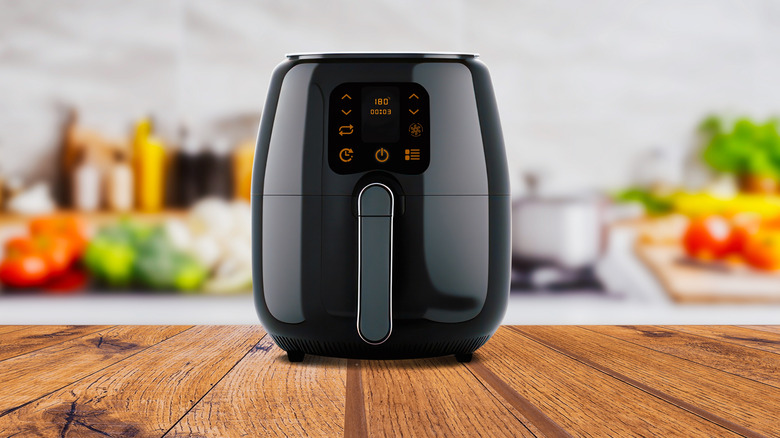 Black air fryer on wood kitchen counter