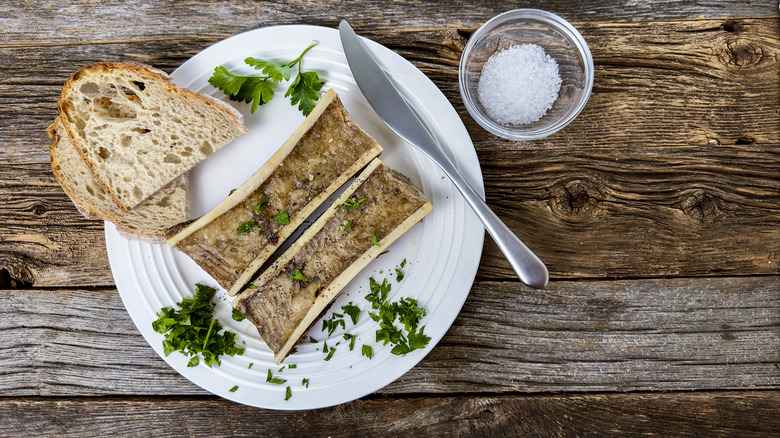 Roasted bone marrow on plate with bread, knife, salt