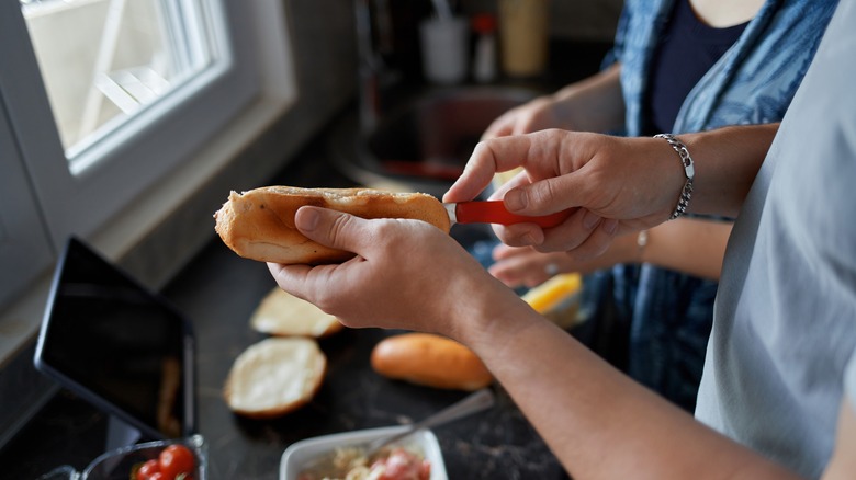 person slices hot dog bun