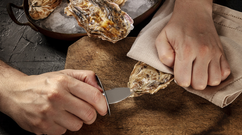 Hands shucking an oyster