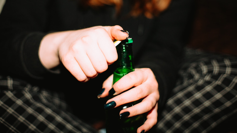 hands with painted nails opening a beer bottle