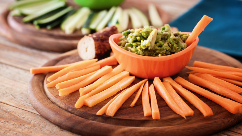 Carrot sticks and dip on a wooden board