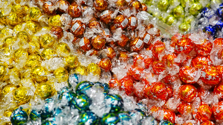 A bin filled with golden, blue, brown, and red Lindor chocolate truffles