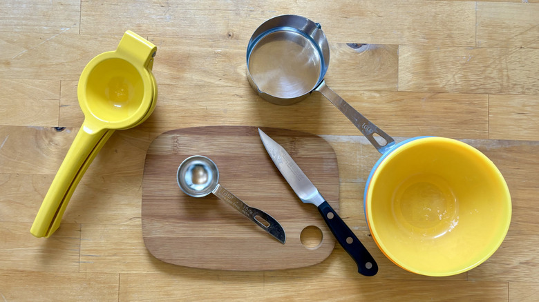 Juicer, bowl, measuring utensils, and a knife sitting on counter