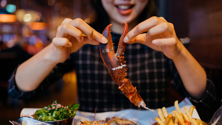 A person holding a lobster claw in a restaurant