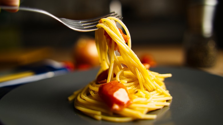 Fork pulling spaghetti from a plate