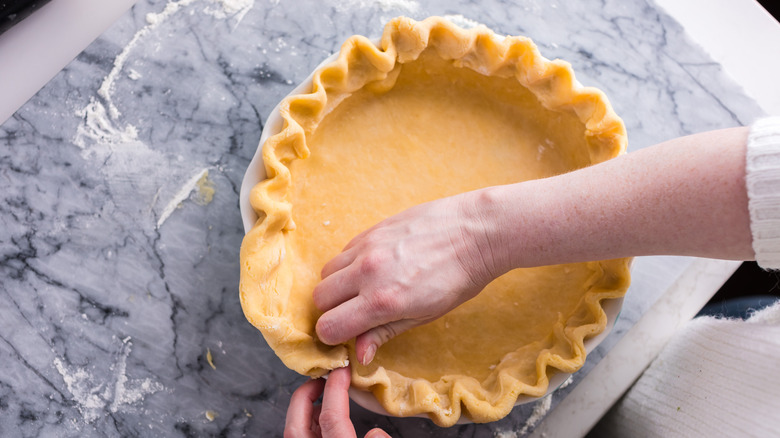 pinching raw pie dough to make pie crust