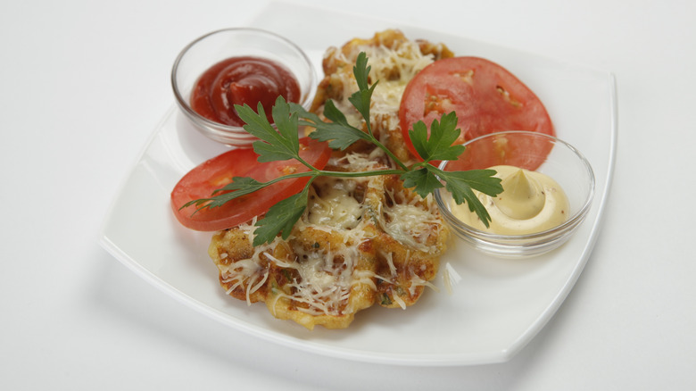 Potato waffles with melted cheese and sliced tomatoes and condiments