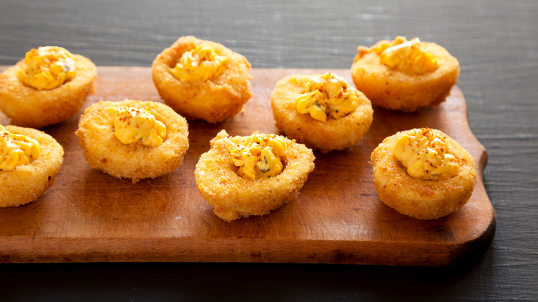 A cutting board covered with homemade deviled eggs fried in oil