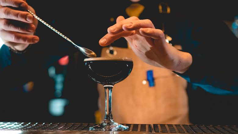 A bartender using a stir spoon to make an espresso martini