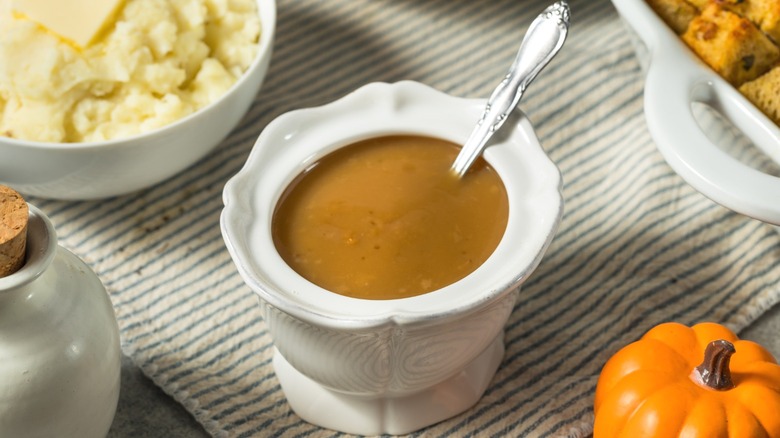 A small bowl of turkey gravy in the middle of a Thanksgiving table