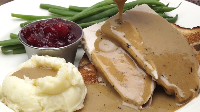 Turkey and mashed potatoes on a plate, doused in brown gravy