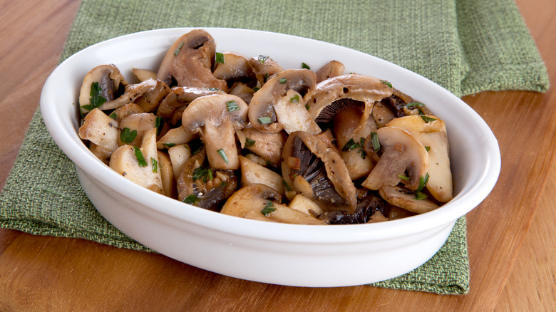 sautéed mushrooms in a white oval dish on a green cloth napkin