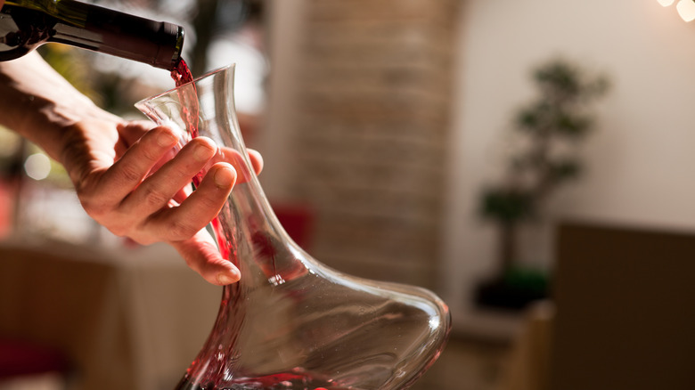 red wine being poured into a long-necked decanter