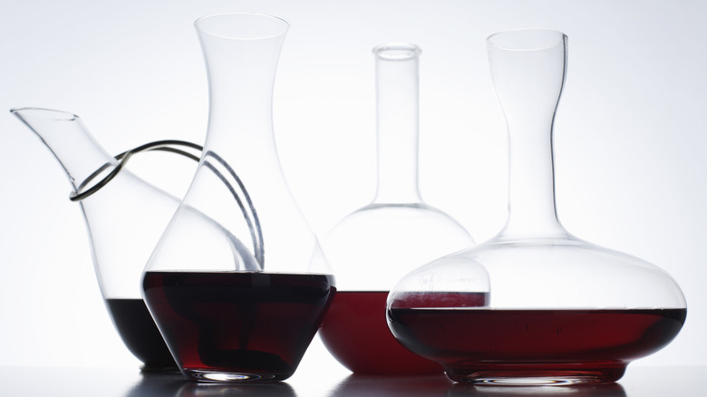 a variety of wine decanters with red wine in them