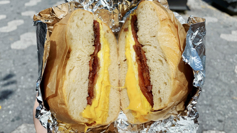 Cut breakfast sandwich with egg, cheese, and bacon in tin foil