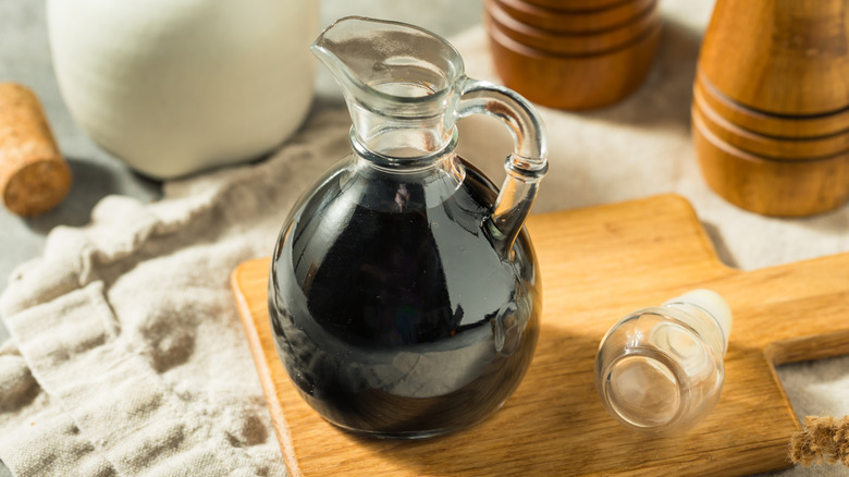 a small pitcher of homemade balsamic glaze sitting on a wooden cutting board