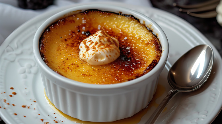 A creme brulee in a ramekin with cream on top