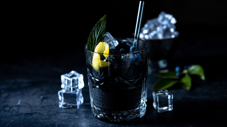 Black cocktail with ice in background