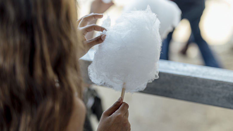 A woman holding a white cotton candy.