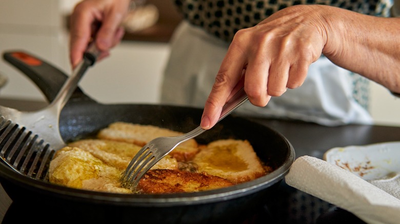 woman frying french toast slices on a frying pan