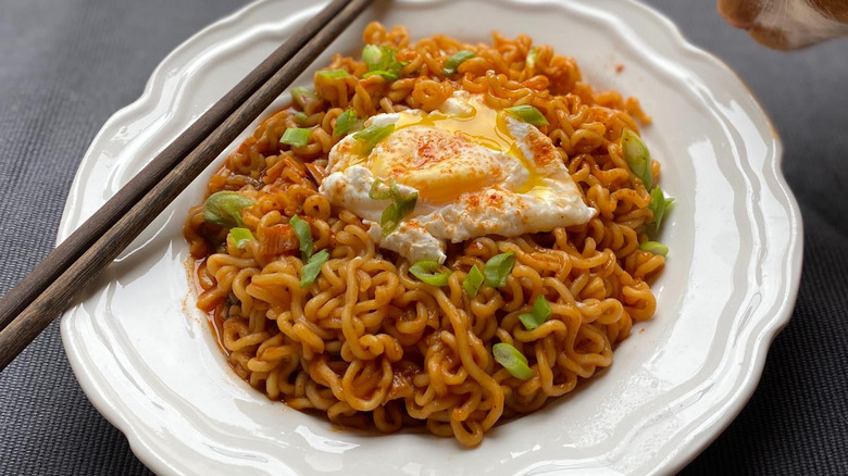 cat sniffing ramen on plate