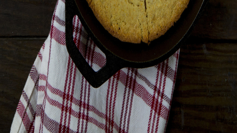 Cornbread inside a cast iron skillet with a few slices missing