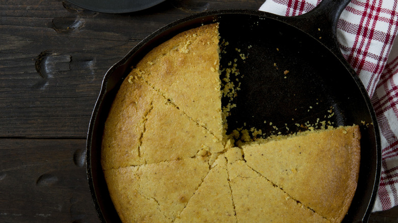 Cornbread inside a cast iron skillet with a few slices missing