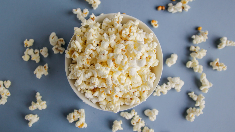 Bowl of popcorn that's spilled over onto the table