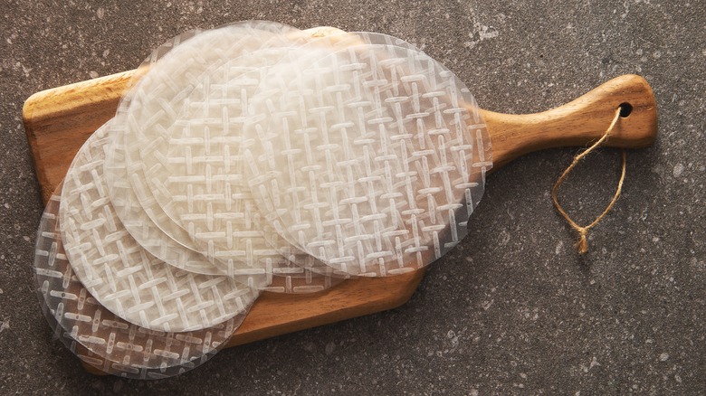 many sheets of rice paper on a wooden cutting board