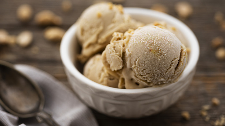 A white bowl filled with vanilla ice cream on a brown surface