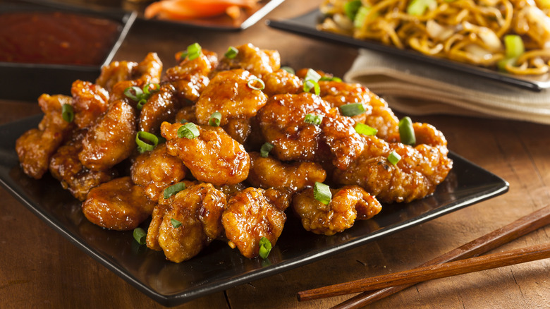 A plate of orange chicken topped with green onions.