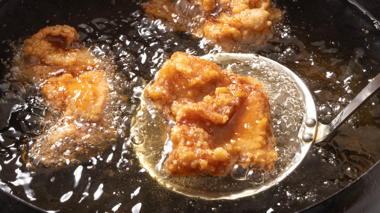 A pot of boiling oil with fried chicken.