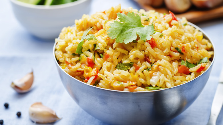 tin bowl of seasoned saffron rice mixed with peppers, garlic, and cilantro