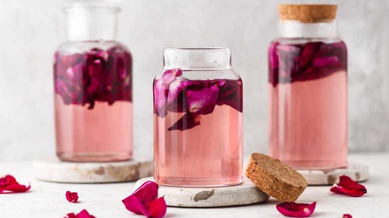 Bottle of pink rose water with rose petals